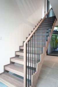 Staircase with iron balustrade and wooden handrail - against white wall