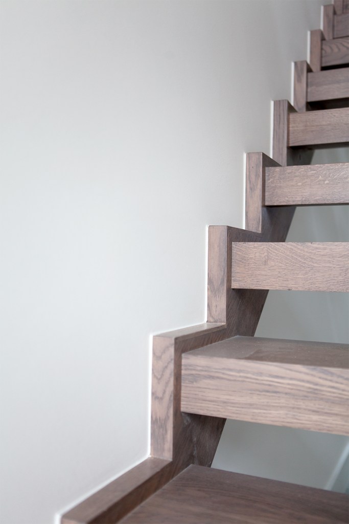 Wooden staircase wall string with wooden tread and gaps between stair treads