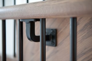 Black stair handlebar bracket - iron bar baluster - close up photo - wooden hand rail