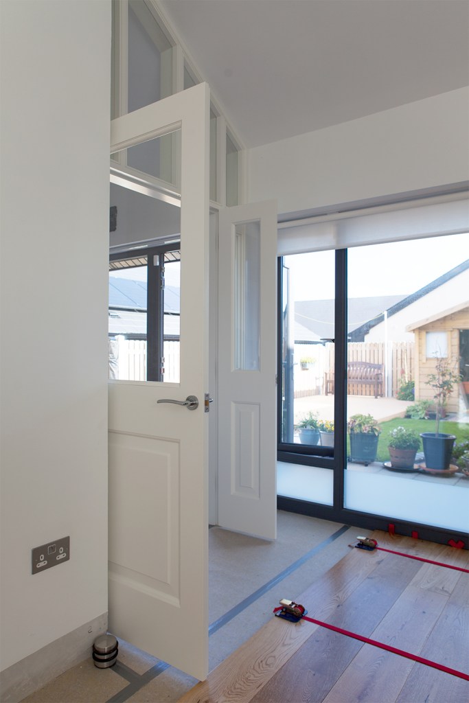 Transom doors opened up - white doors with windows - windows above doors - white door frame - big windows with black frame