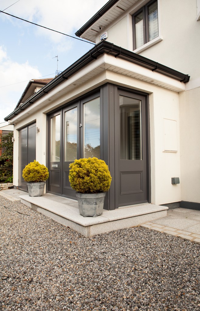 black frame window - black frame door - glass in door - pot plants - gravel - white house