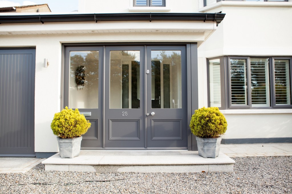 Front door - door with glass - door frame with glass - dark grey door - pot plants - gravel - windows with black frame - window shutters