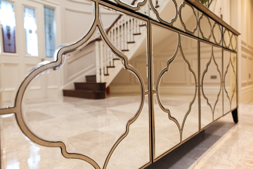 glass decorative serving table with a reflection of stairs - dark wood stairs - white stair railing - transom door reflection