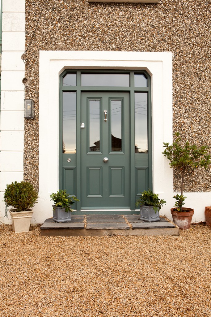 front door with white frame - dark color door with windows in the middle and the side - gravel - entrance - gravel wall