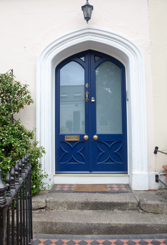 Blue door with privacy windows in the door - white arch around the door with black lantern light at the top - front door - steps to door - gold door knobs