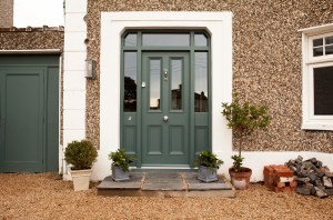 Front door - green door - silver door knob - entry - gravel - green garage door - windows in door - door frame - green door frame - frame with windows
