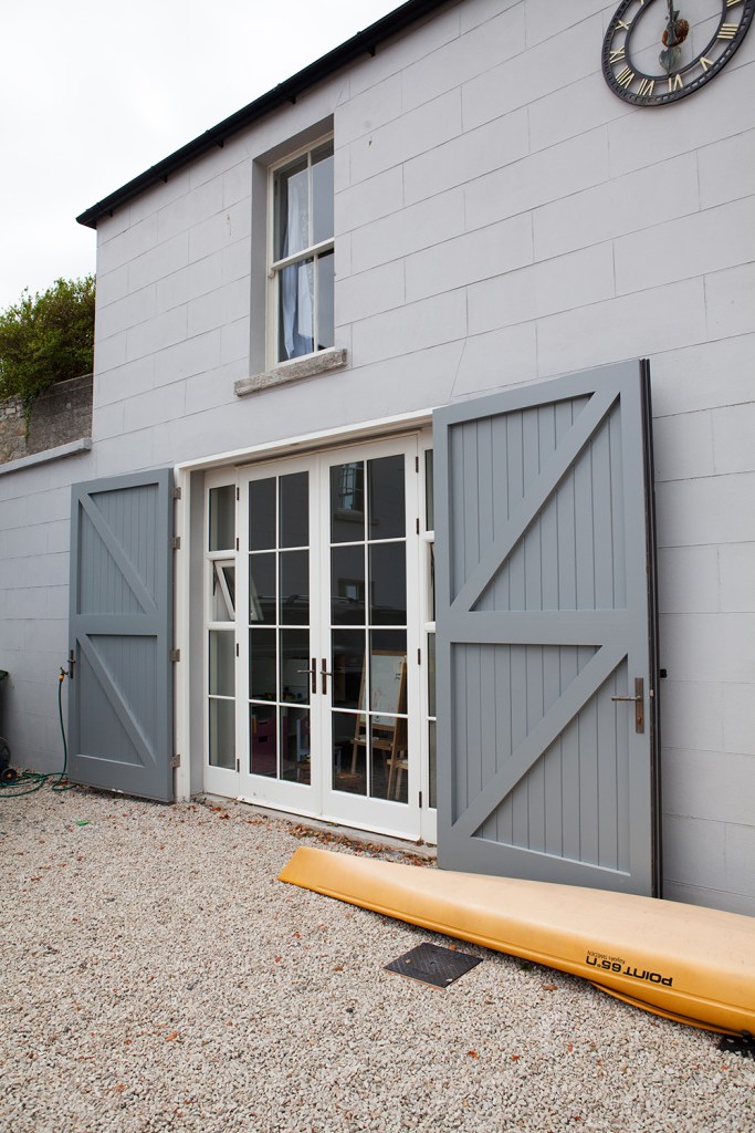 Grey double doors opened up with transom doors closed - sidelights - yellow kayak - clock on wall - gravel
