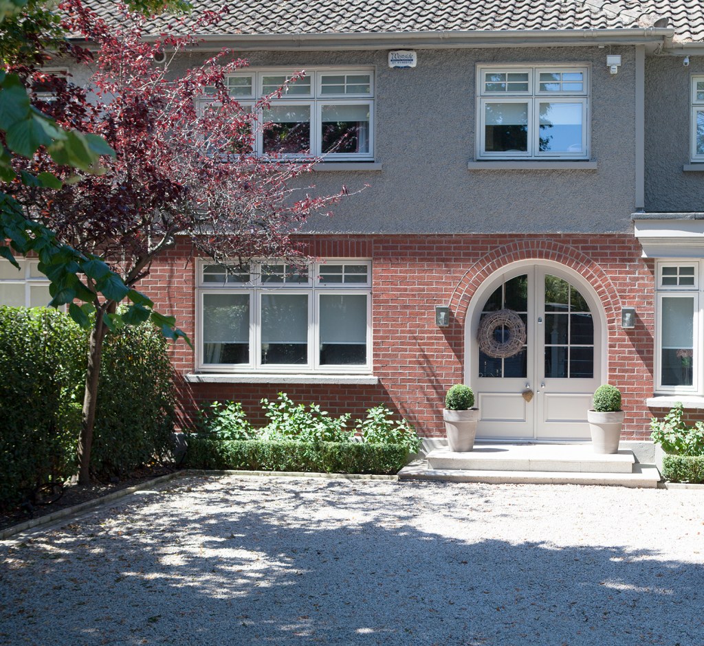 Transom arched door - white door - red brick frame - windows with white frame - gravel - front door - tree's