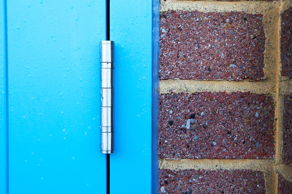 Blue door with silver hinge - blue door frame - brick wall