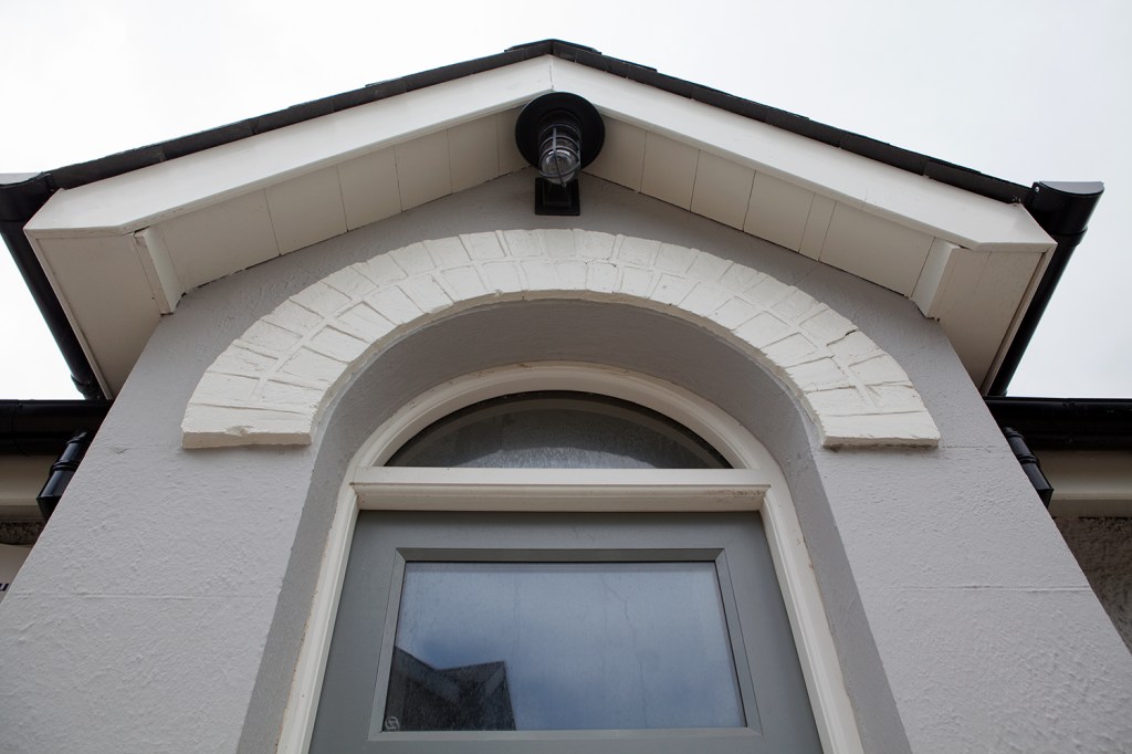 Window with black frame and white arch around - white brick arch at top and black lantern light under roof