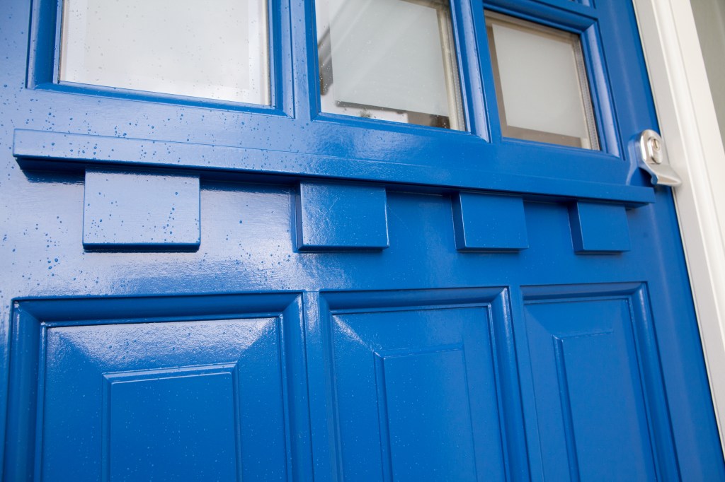 Blue door with windows at top - white door frame - transom door - wood carving in door