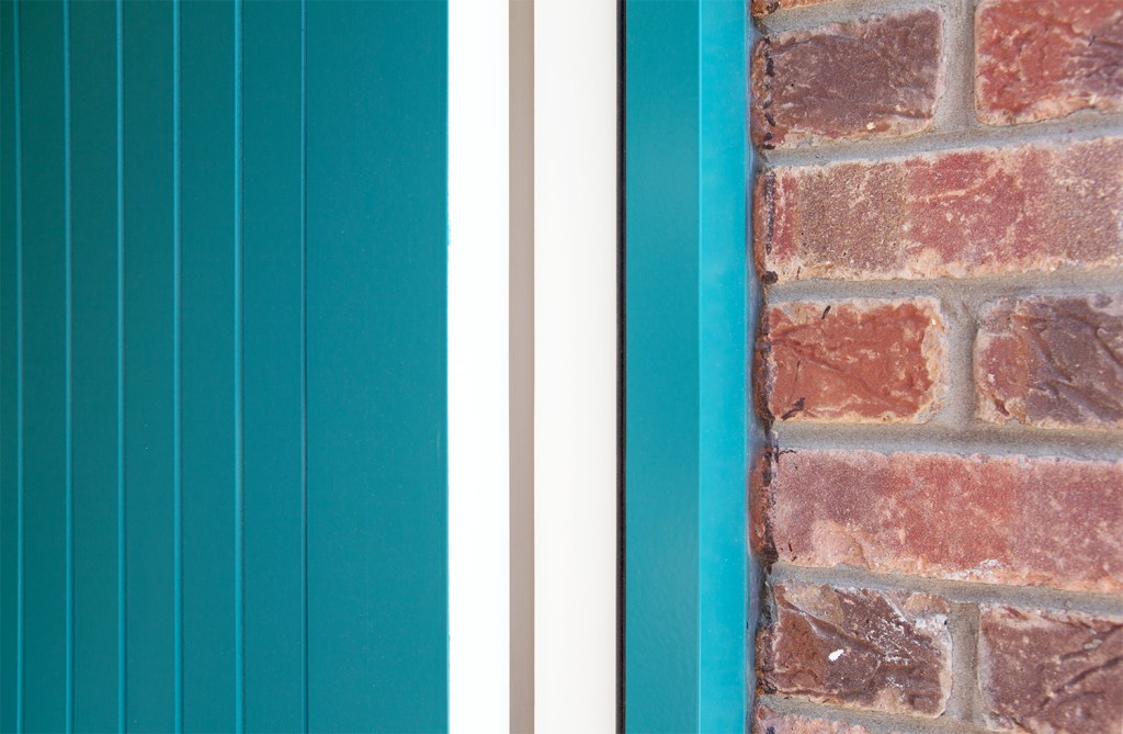 Exposed door frame - turquoise door - white door frame - brick wall