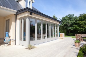 House from outside with glass doors and windows. Wooden deck.