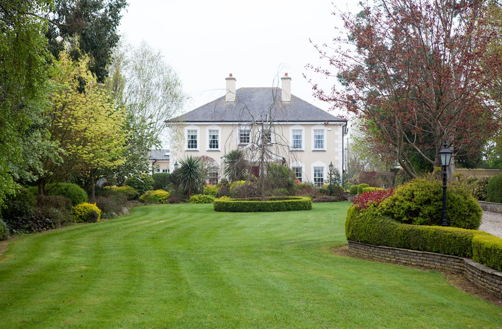 manicured lawns-cape with a double story house in background - double chimney - tree's - landscape - white window frames