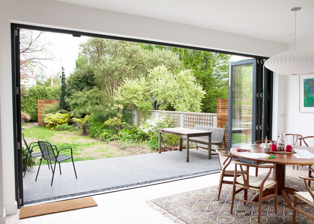 Open plan dining room connected to outside - open stacker doors - open bifold door - natural light - outside connecting to inside - patio - garden view
