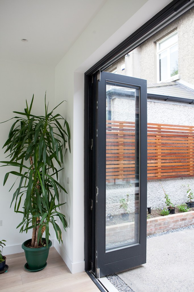 Pot plant in the corner - black bifold doors - opened stacker doors with black frame - glass door