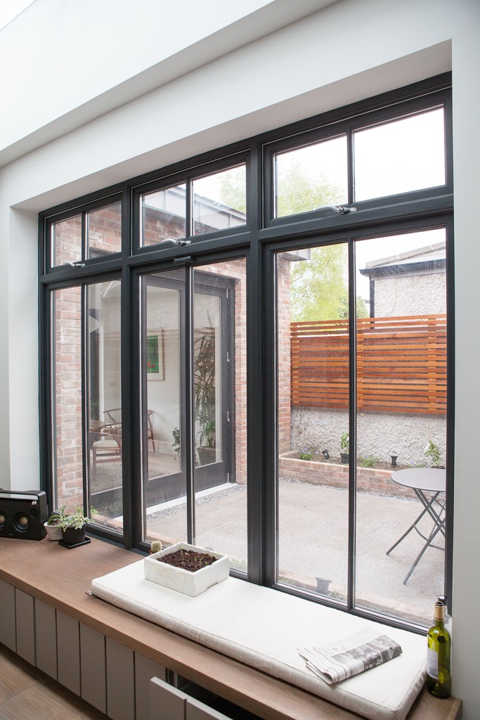 Big windows with black frame and black grilles - small seating next to window - windowsill - white wall arch - clerestory windows