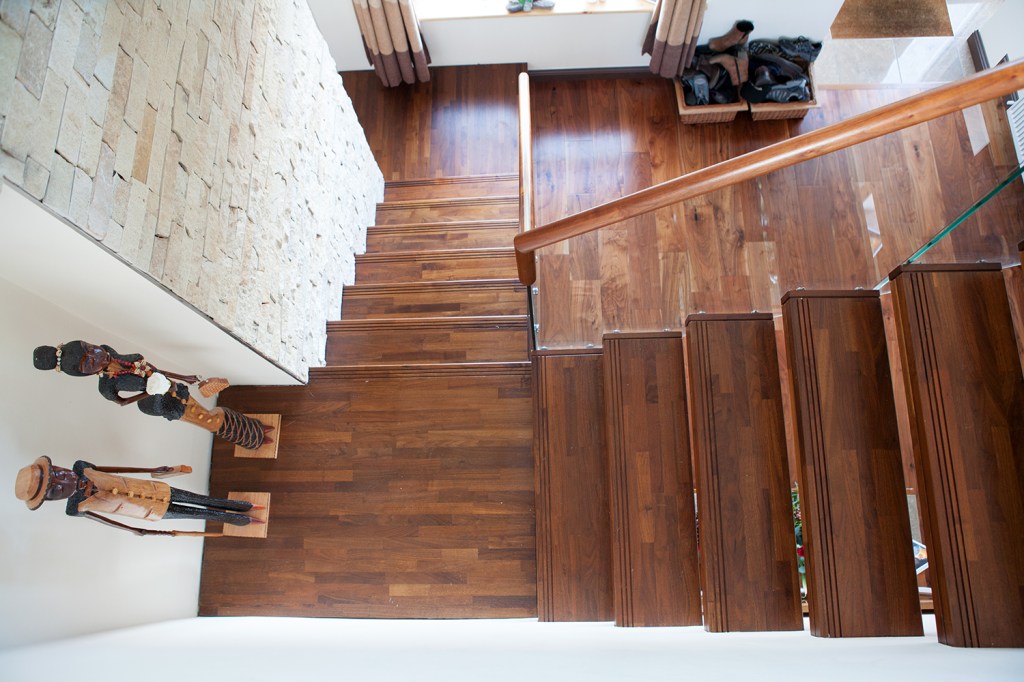 View from top - top view cantilevered staircase - wood stairs - timber treads - stone wall - wooden floor - standing ornaments - glass balustrade