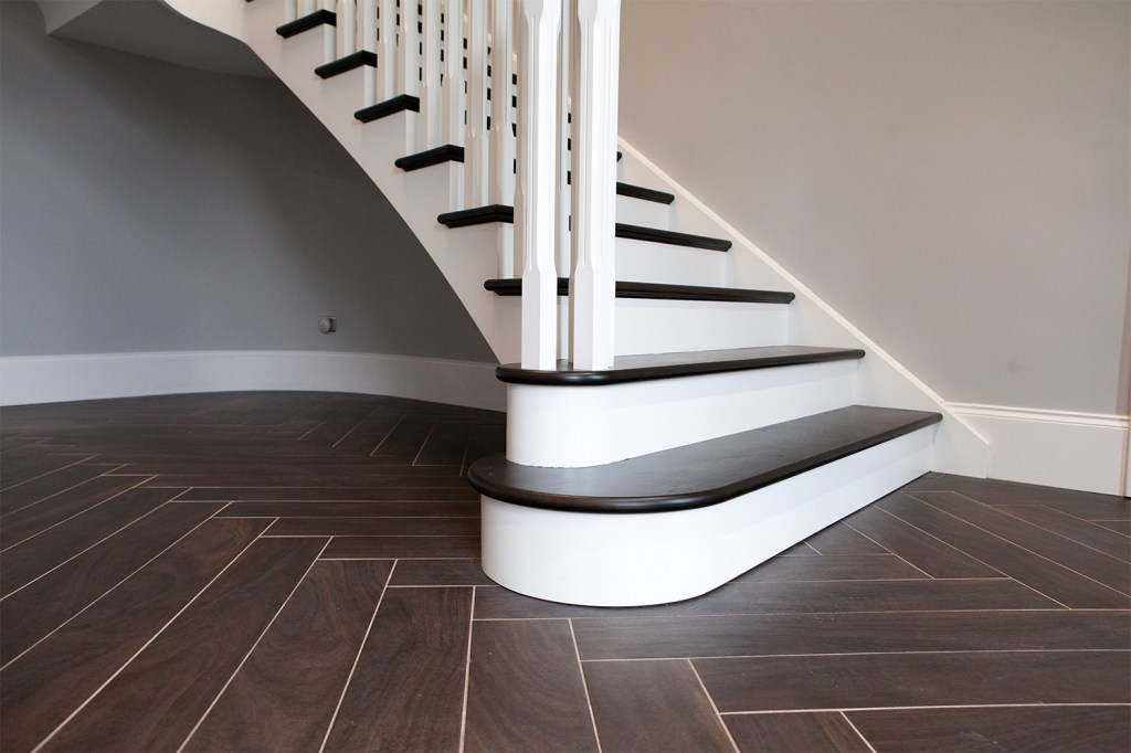 White stair riser - bottom stair - black nosing of stairs - white baluster and newel - laminated floors