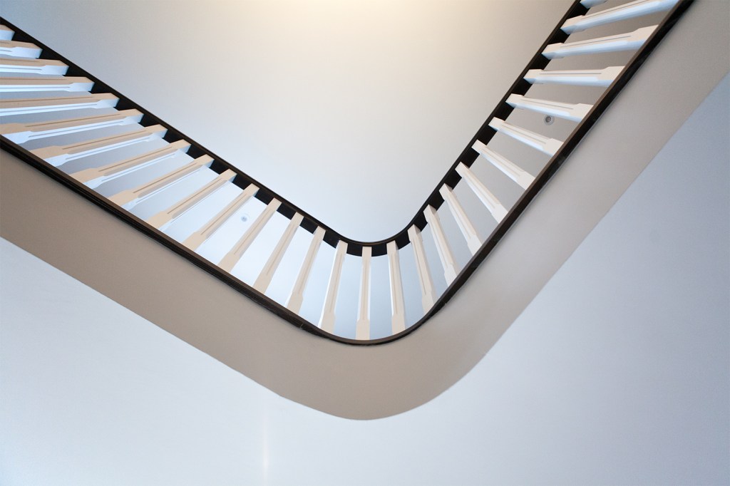 White baluster curve with dark handrail - inside balcony - looking up - white roof and wall
