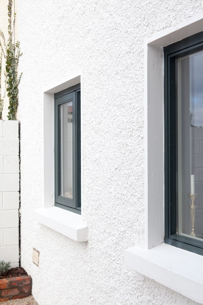 Simplistic windows with black window frames and white arches and skirting for windows - white house wall - outside view