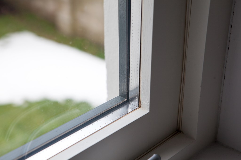 Window corner - white inside window frame - lower sash of window - black outside window frame - aluminum inside frame