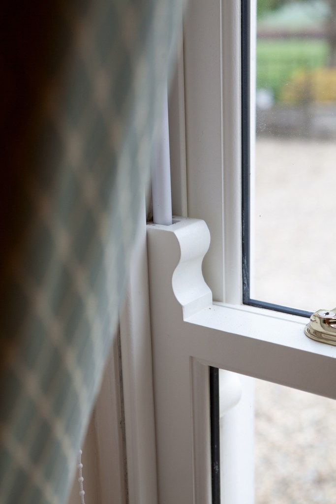Looking past a curtain at a double hatch window and details of the sliding frame