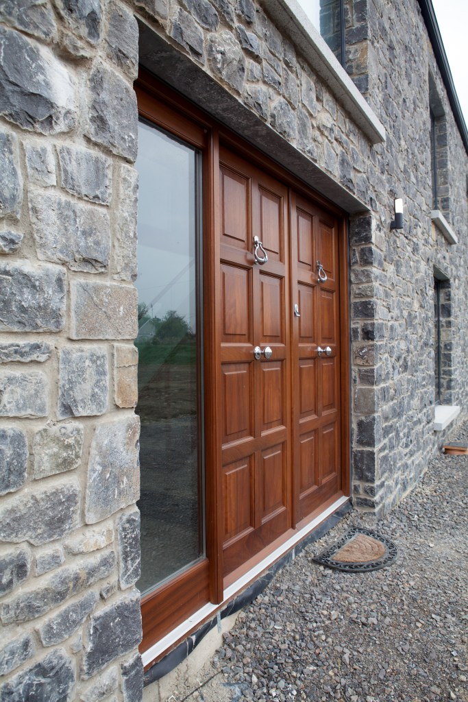Double wood door - side view - glass window next to door - stone wall