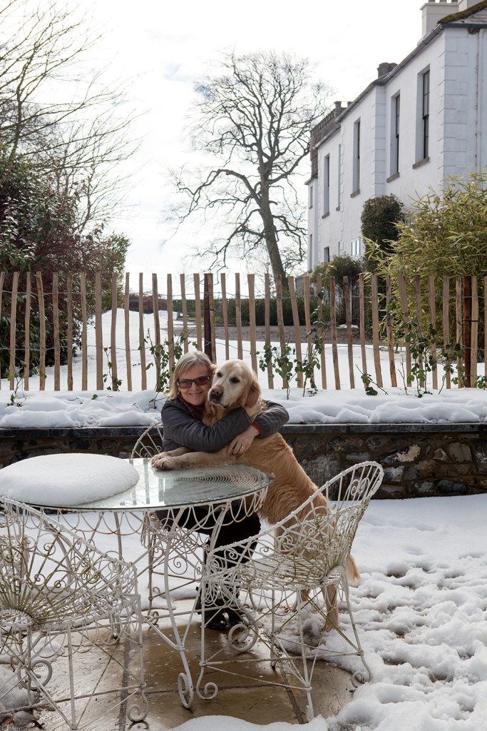 Women hugging dog whilst sitting at table in snow